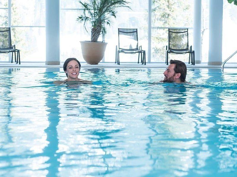 Eltern schwimmen im Hallenbad des Familienhotels Alphotel